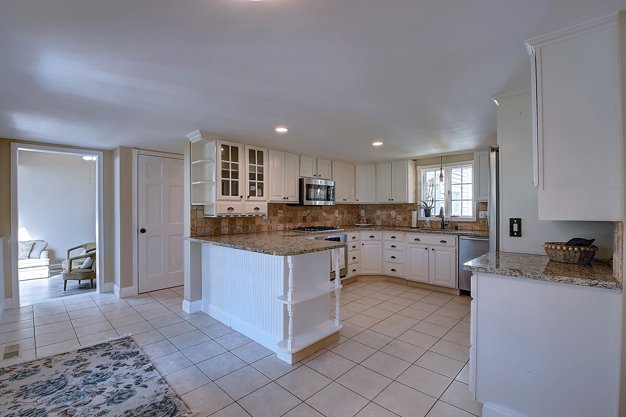 Kitchen with white cabinetry, granite counters, and tile flooring