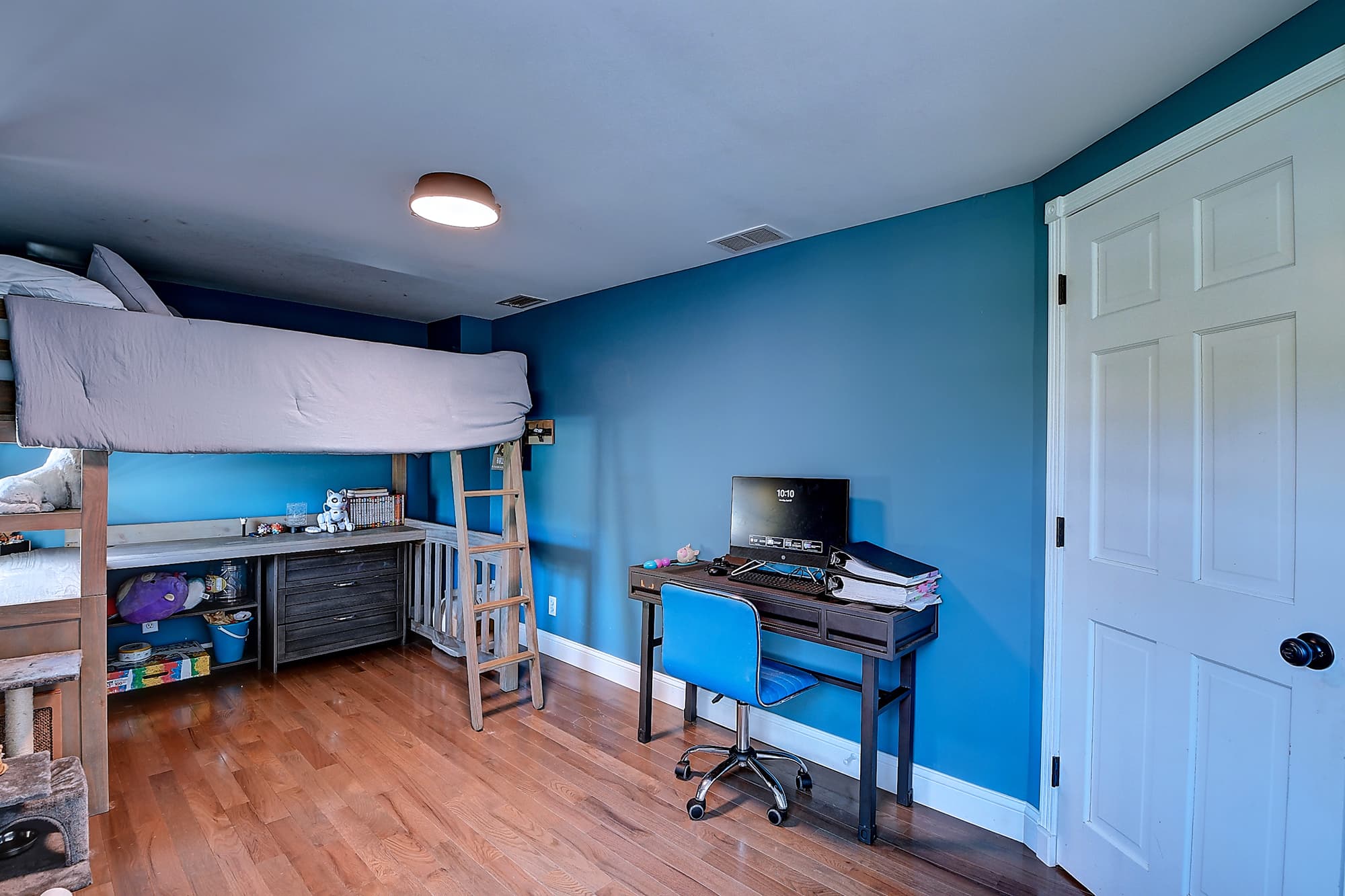 Bright bedroom with loft bed and built-in desk workspace, ideal for a child's room or flexible study space